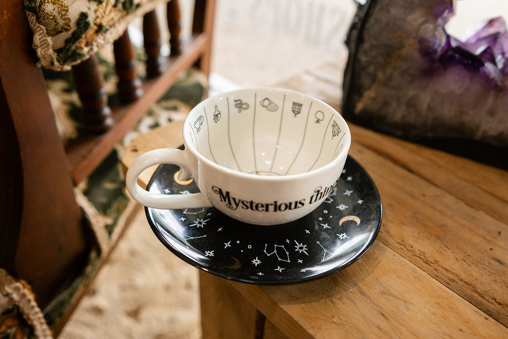 Tea Cup & Saucer Set on a wooden table surrounded by a crystal display and chair