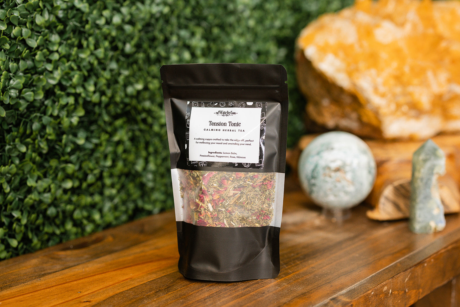 Tension Tonic Tea Blend displayed on a wooden benchtop with crystals displayed in the background