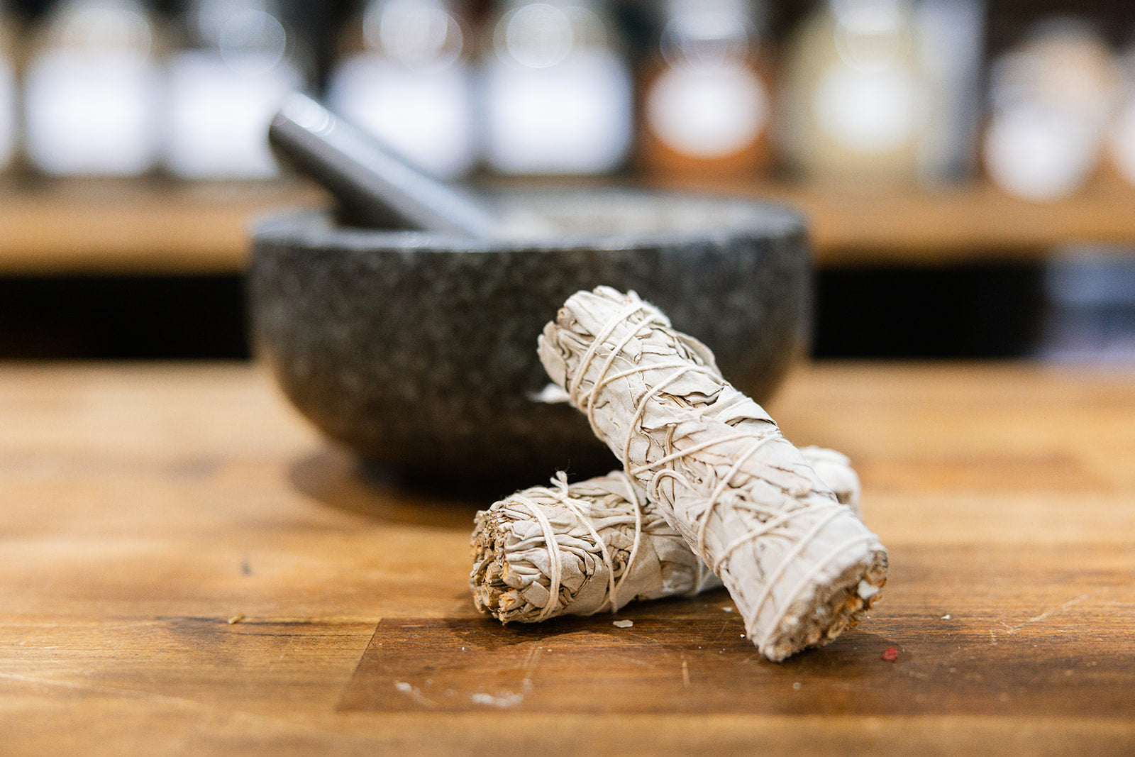 White sage smudge sticks on timber bench with mortar and pestle in background