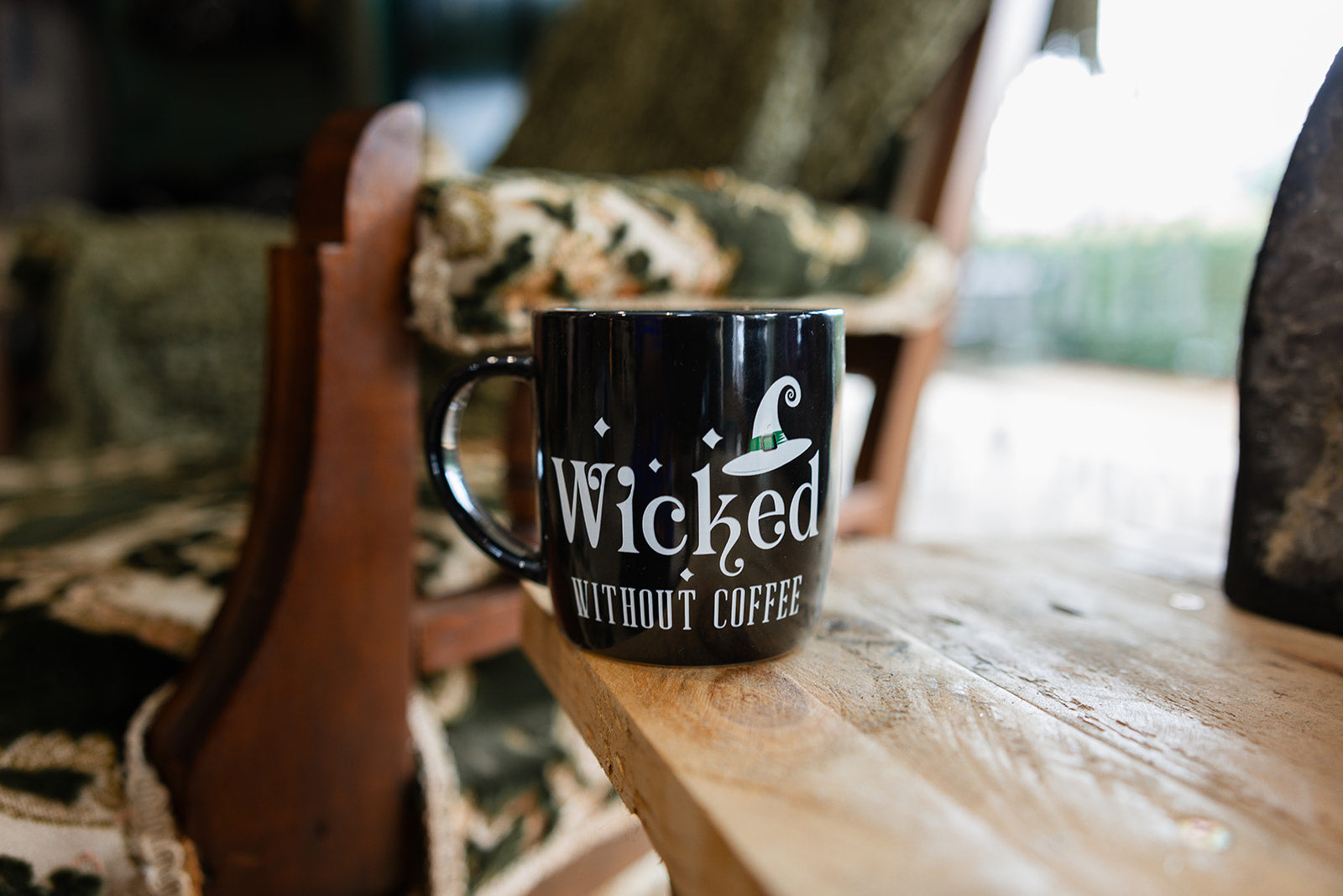 Coffee mug displayed on wooden bench with the wording on the mug Wicked Without Coffee Mug