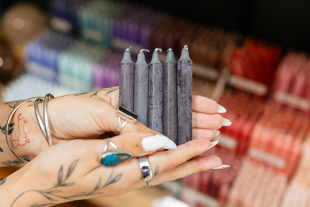 Person holding black spell candles with blurred background
