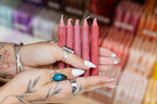 Person holding red candles with tattoos and nail polish details
