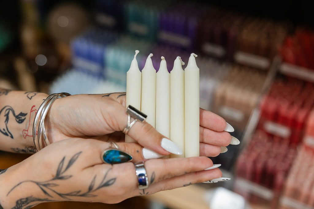 Hands holding cream candles with a blurred store background