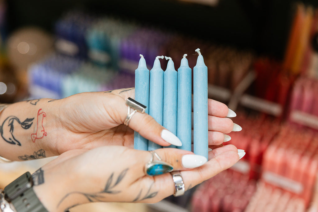 Hand holding teal candles with a blurred store background