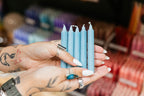Hand holding teal candles with a blurred store background