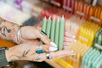 Person holding green candles with a blurred store background