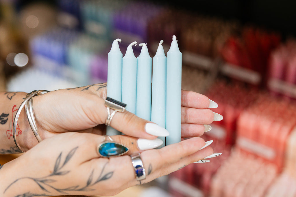 Hands holding four blue candles with a blurred store background