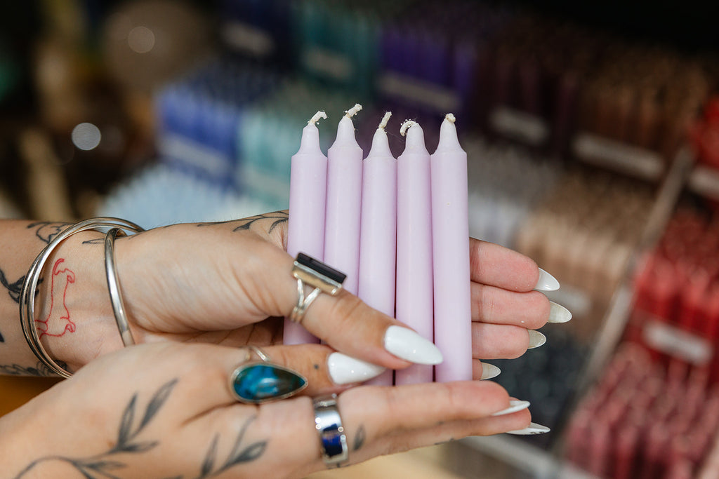 Hands holding pink candles with a blurred store background
