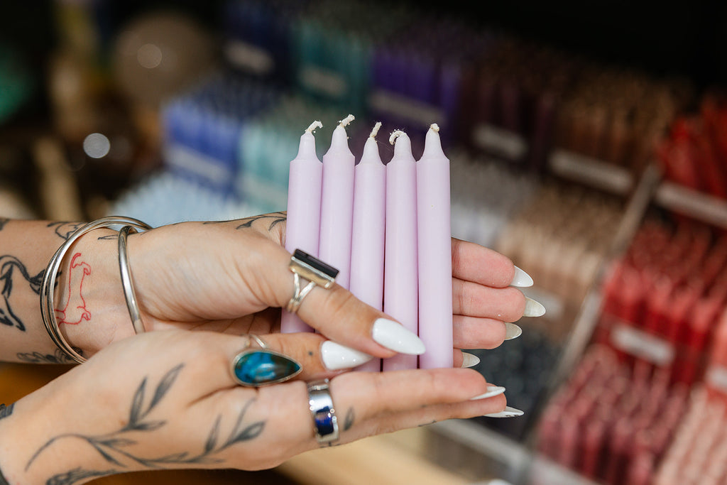 Person holding lilac candles with a blurred store background
