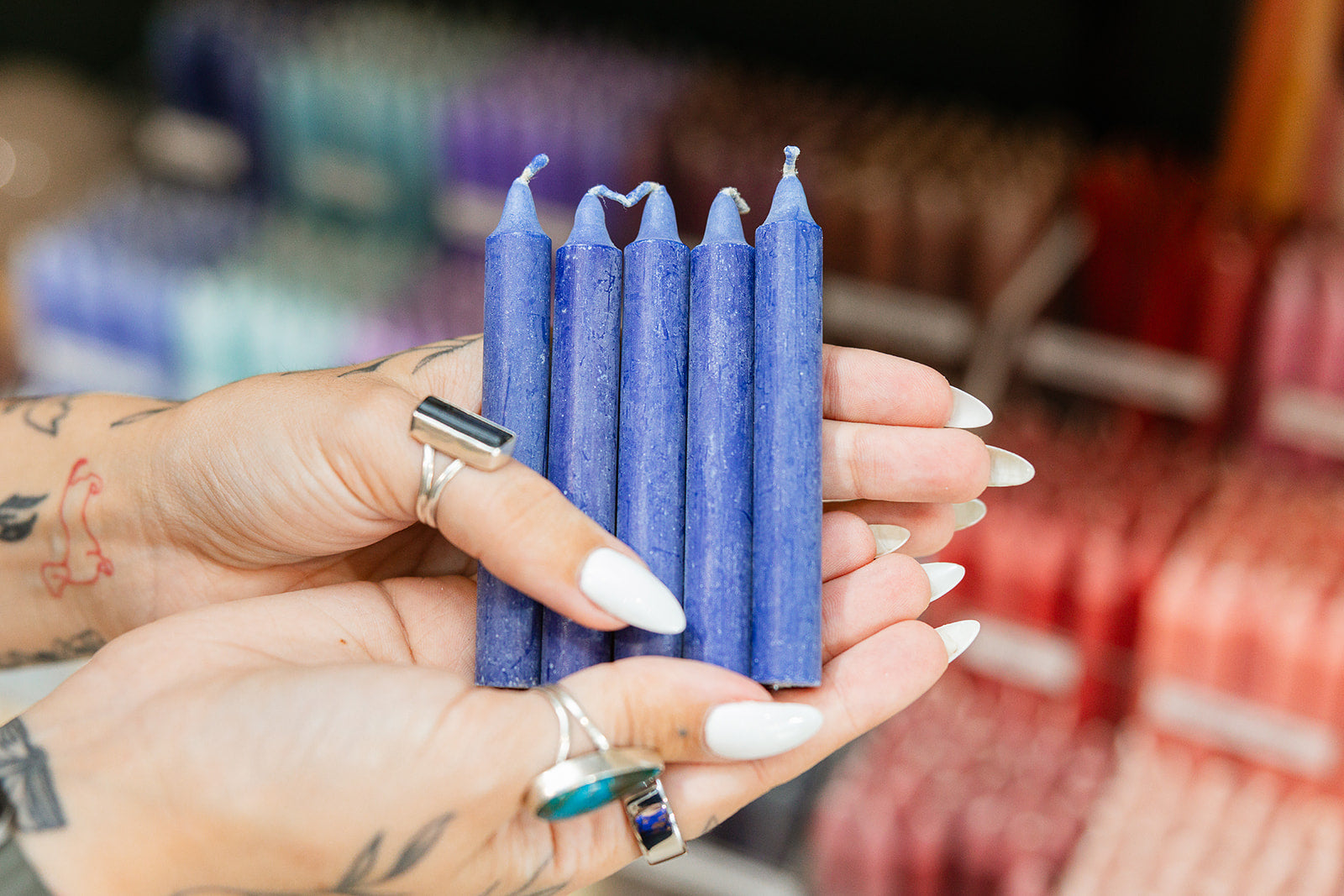 Hand holding six navy blue candles with a blurred store background