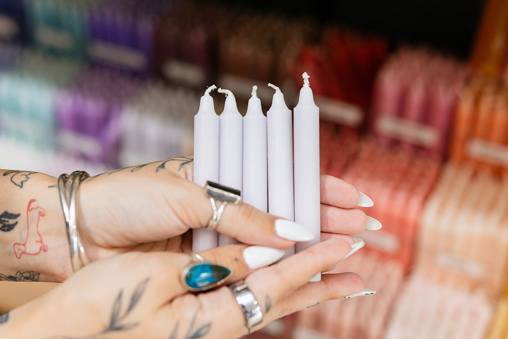 Person holding silver candles with a blurred background of colorful items