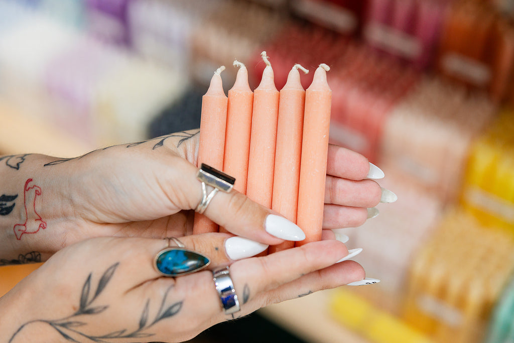 Person holding six peach-colored candles with a blurred background