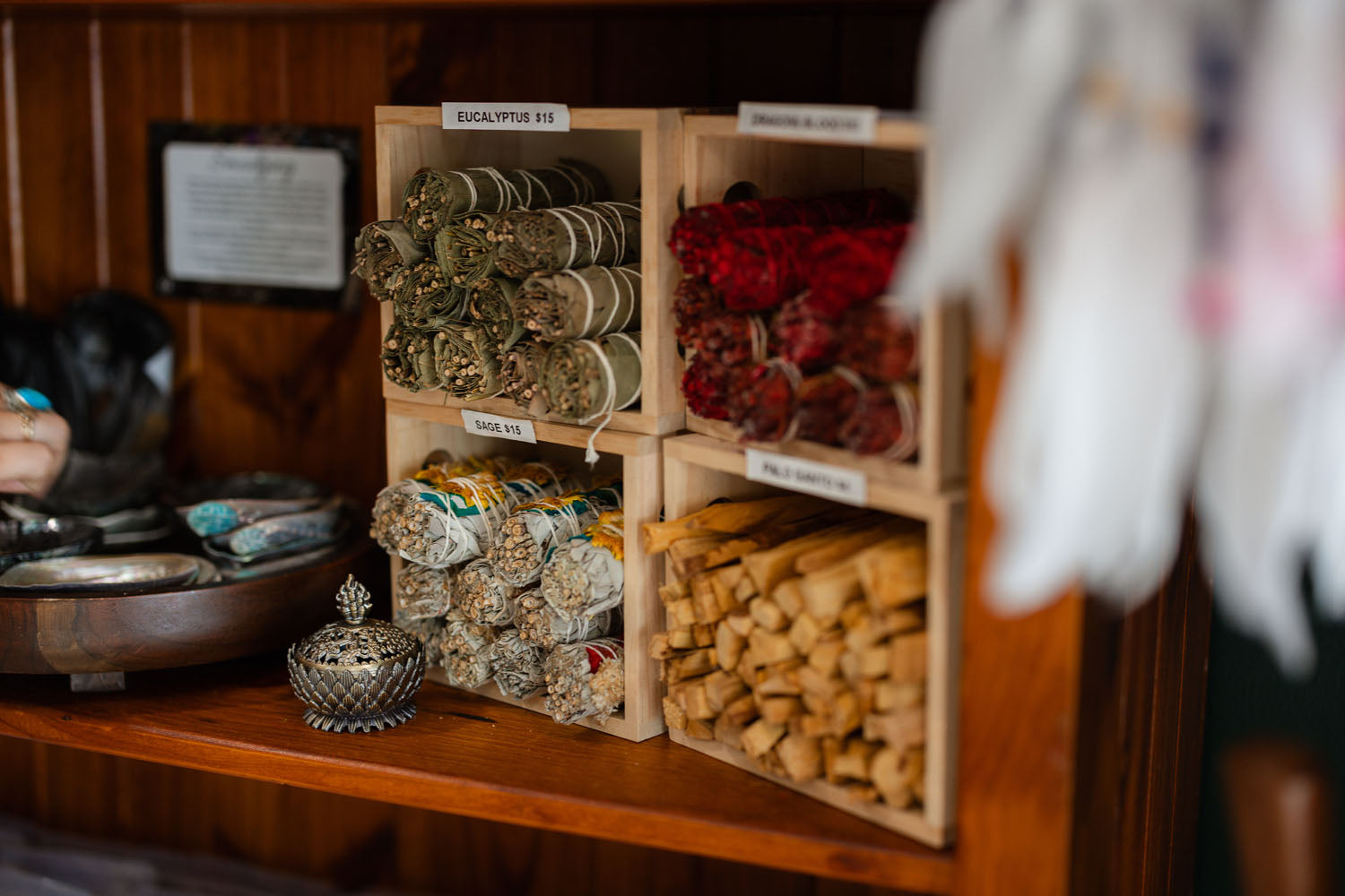 Wooden crates with rolled-up herbs, smudge sticks and dried flowers on a wooden shelf