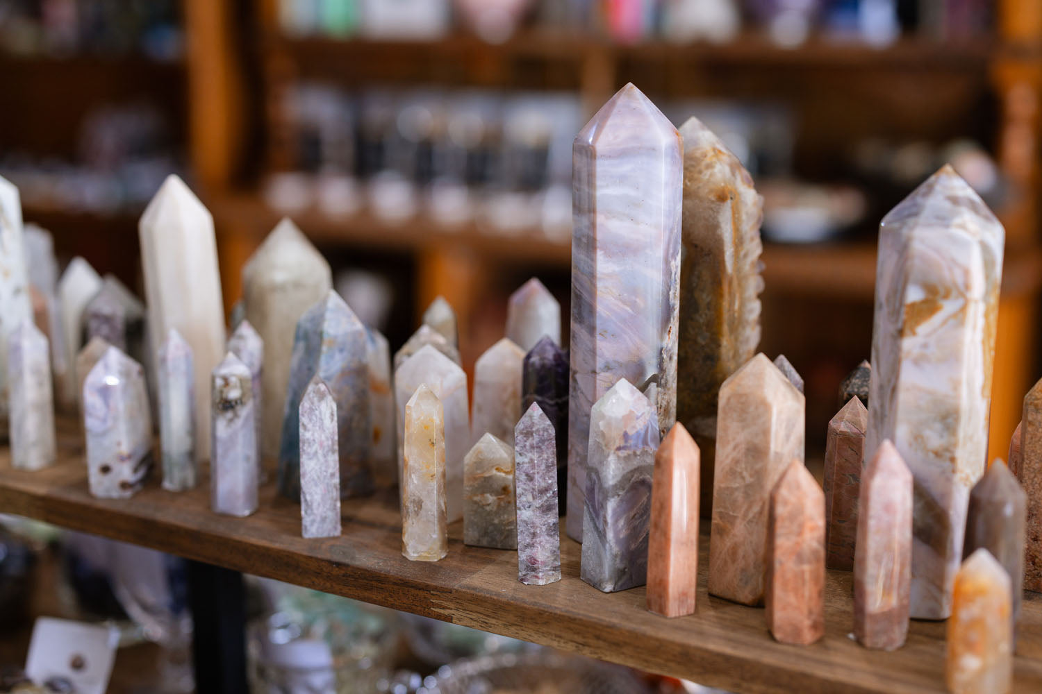 Collection of crystal and stone points on a wooden shelf with a blurred background.