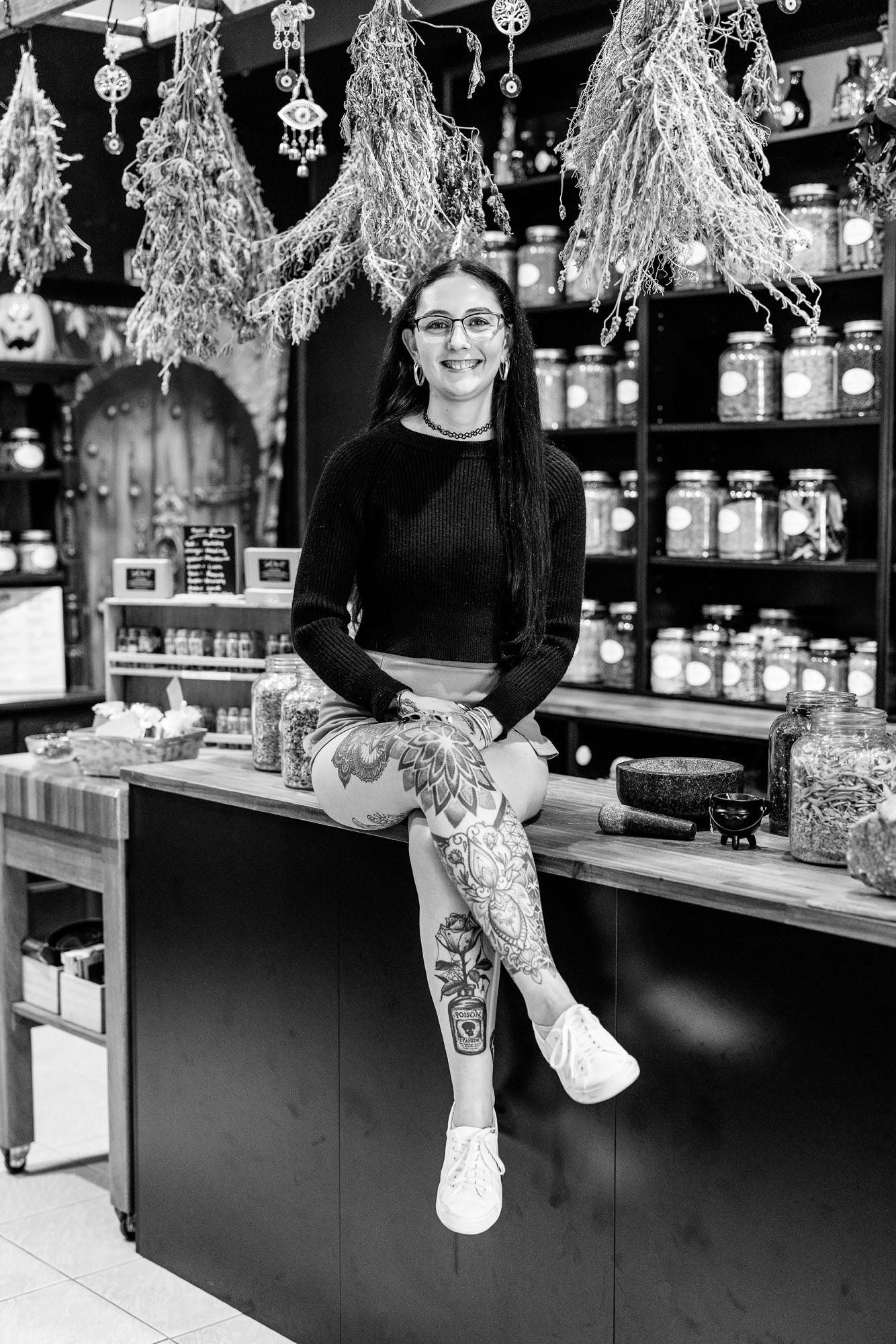 Person sitting on a counter in a store with shelves of jars and decorative items.