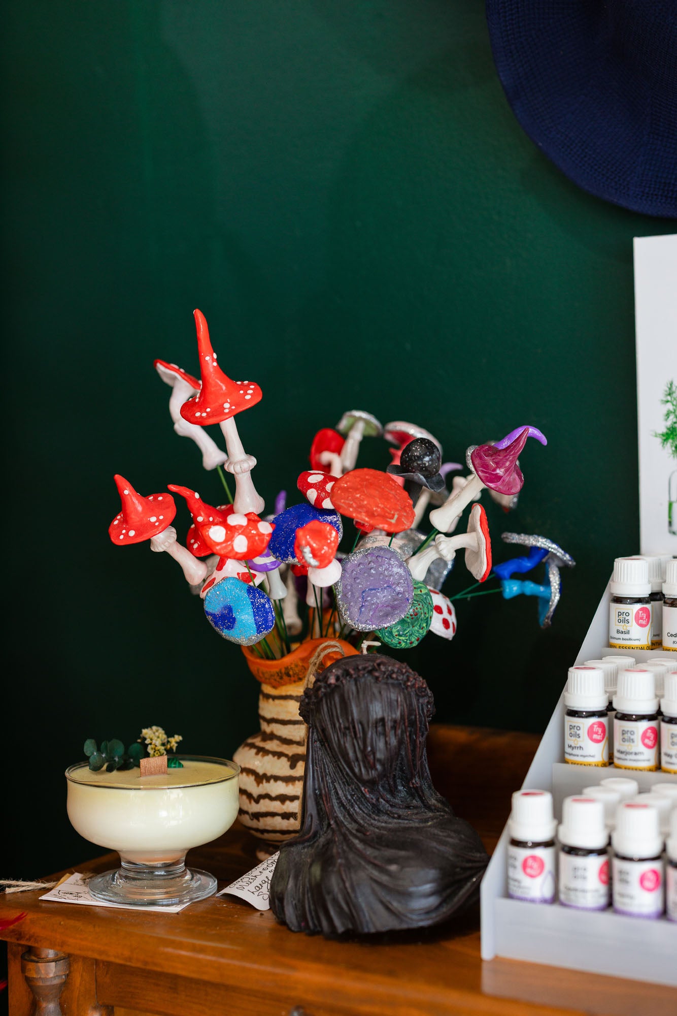 Colorful glass flowers in a vase on a wooden table with a dark green wall in the background.