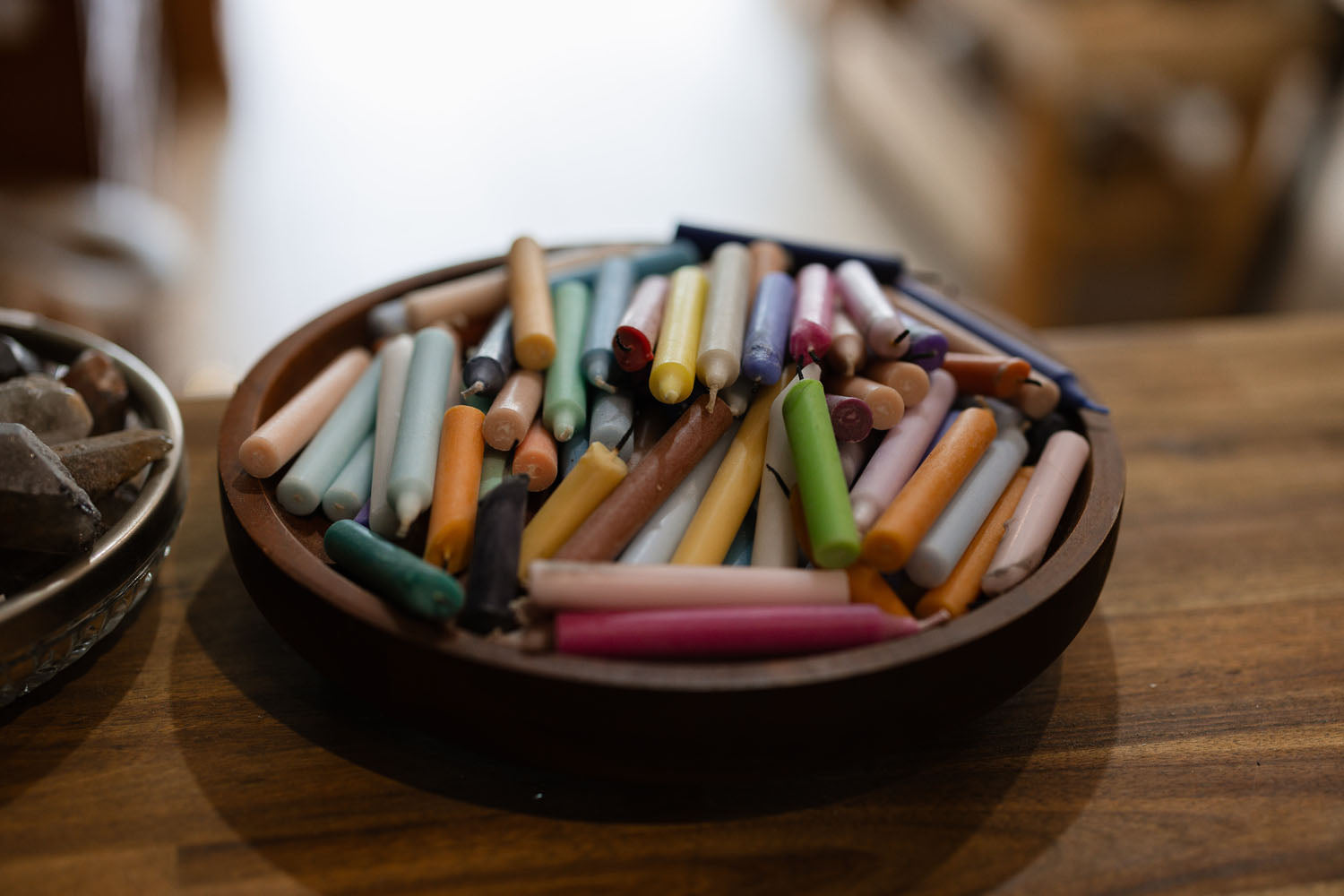 Assorted colourful candles in a wooden holder on a wooden surface