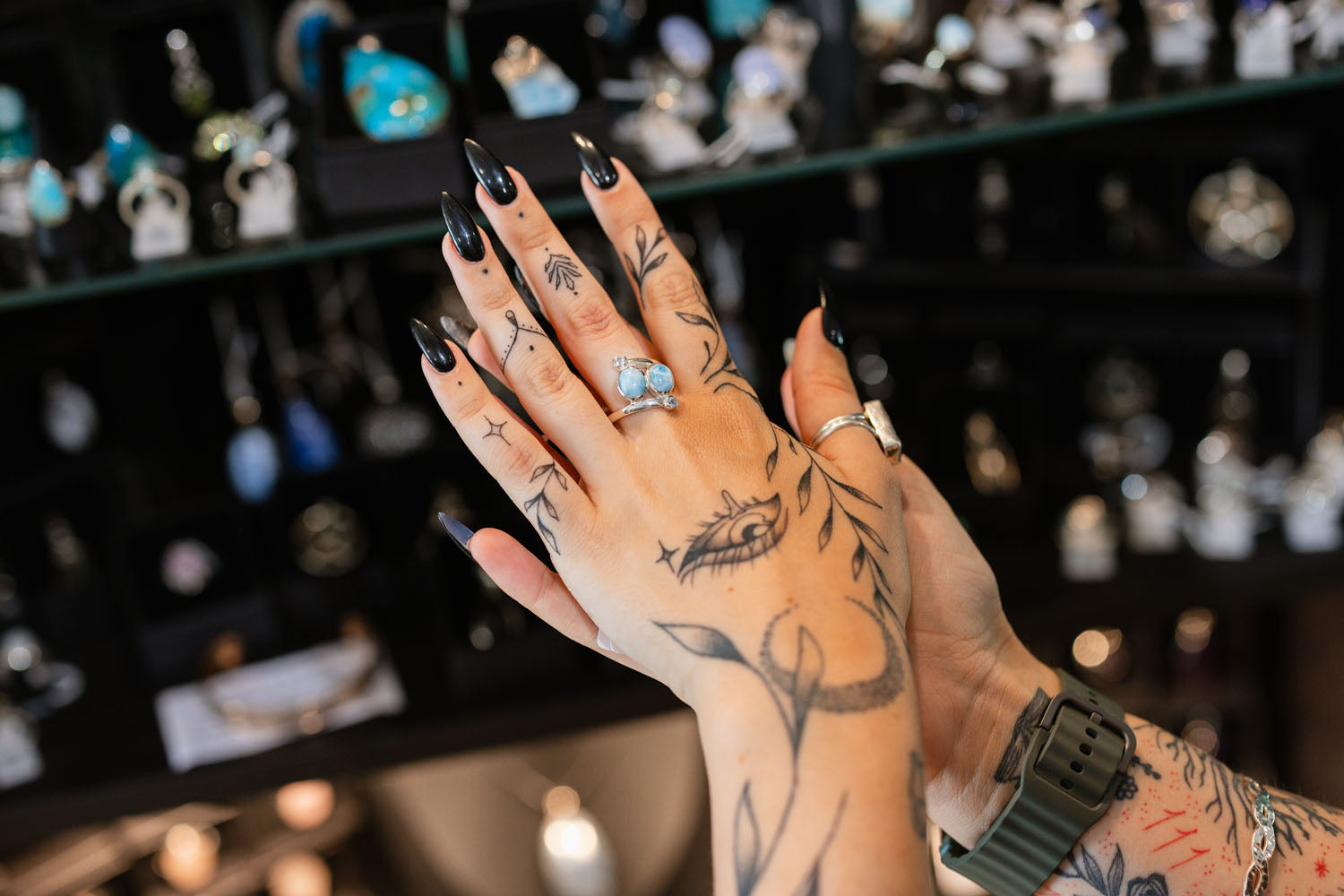 Close-up of tattooed hands with rings against a blurred bar background