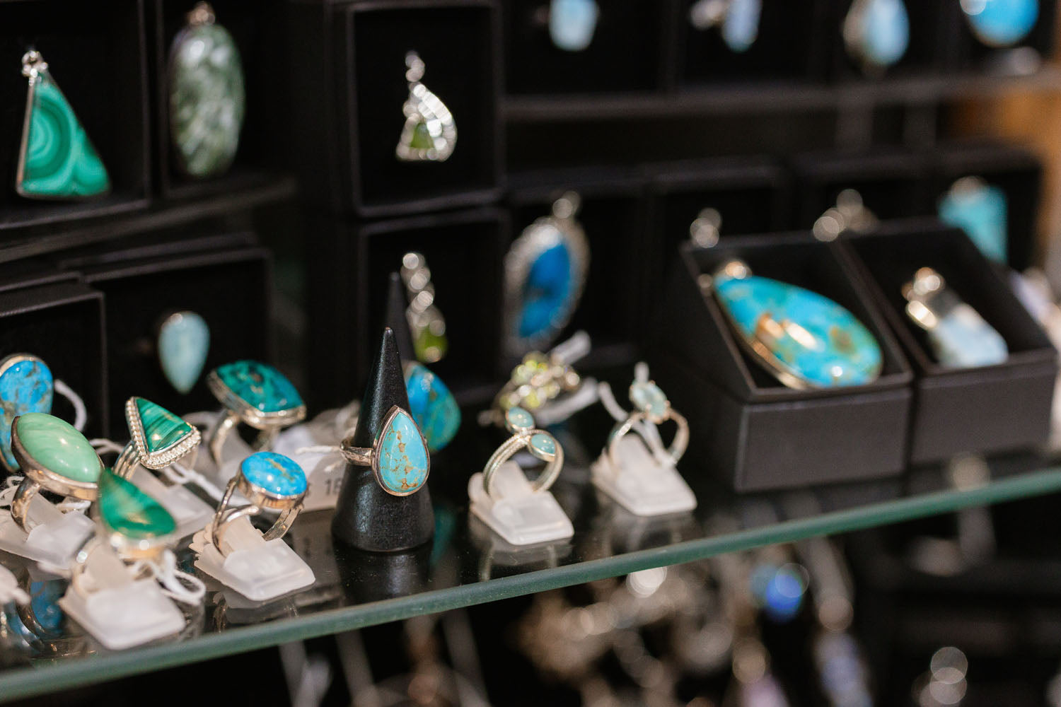 Jewellery display with turquoise stones on a glass shelf in The Witchy Nook.