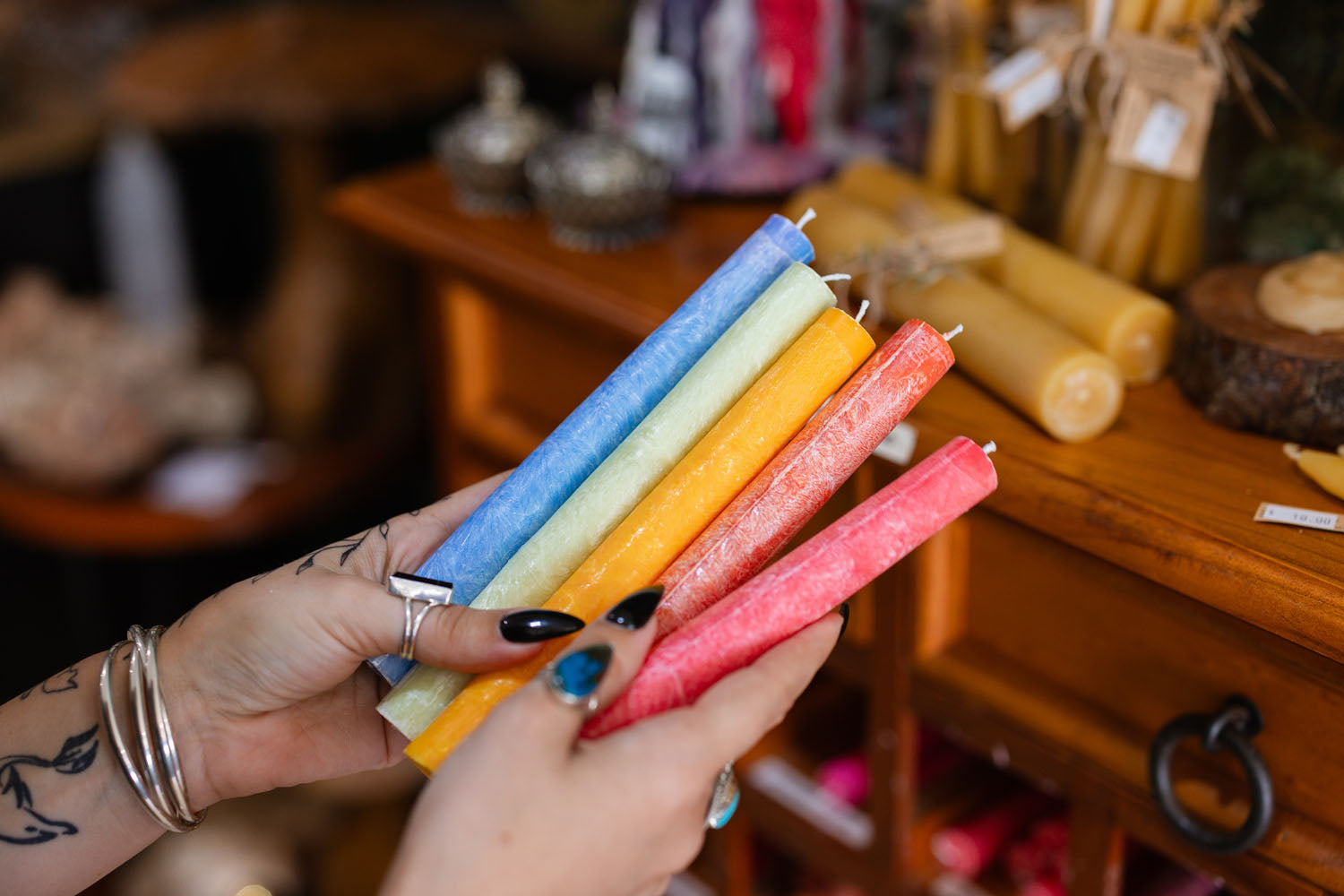 Colourful candles held by hands in The Witchy Nook