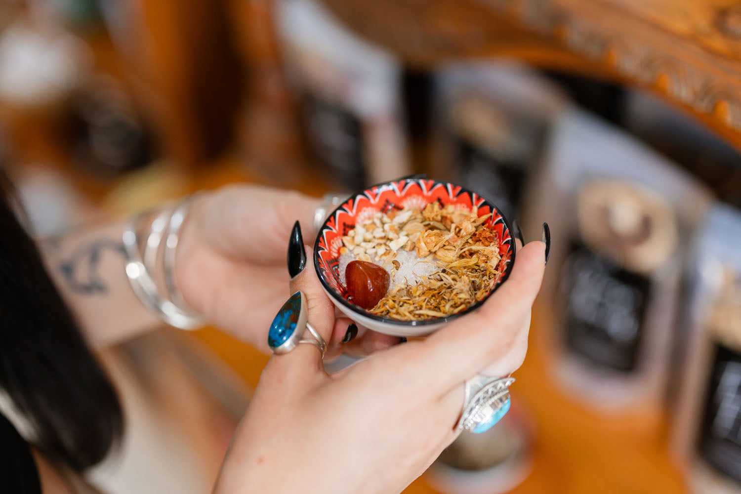 Person holding a bowl of spell ingredients with a blurred background