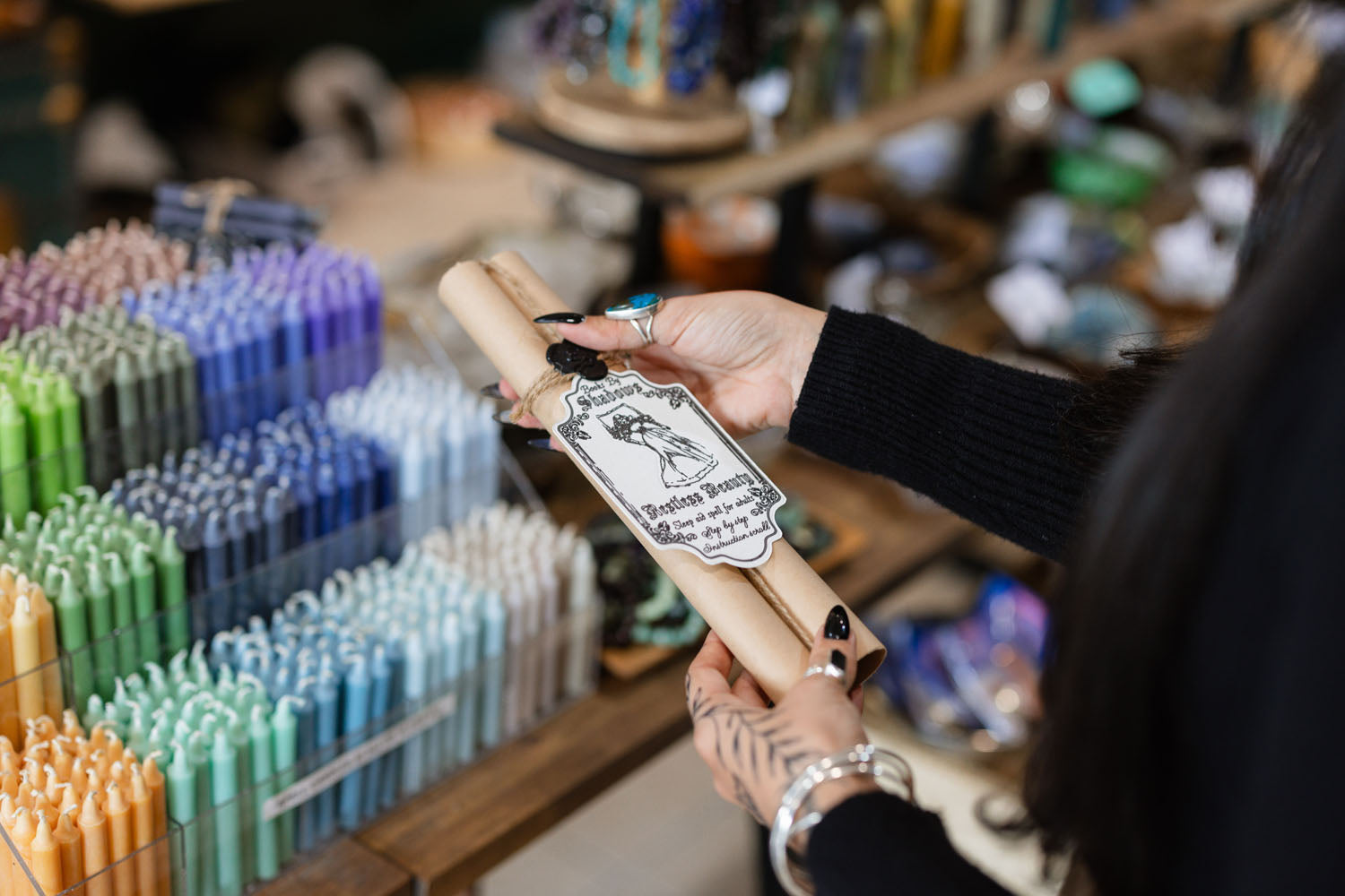 Person holding a roll of paper with a label in front of many colourful candles.