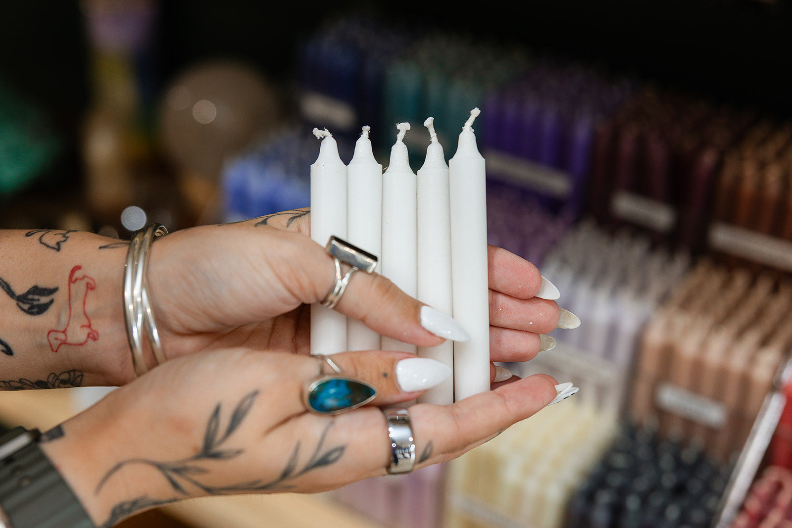 Person holding white candles with a blurred store background